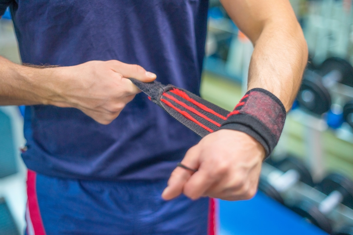 Man questioning while looking at weightlifting straps symbolizing the debate if lifting straps are considered cheating