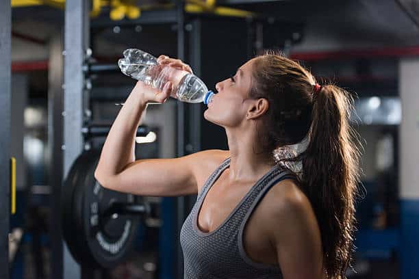 woman drinking water at gym